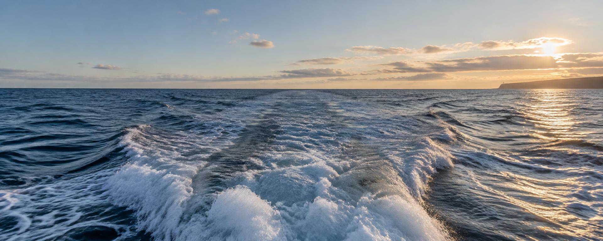 A fishing boat’s wake across the open Atlantic in late afternoon light